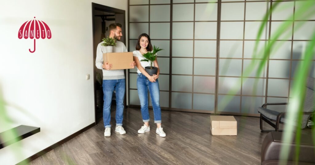 Lidé před stěnou s klíči a kufrem – symbol pronájmu, stěhování nebo krátkodobého ubytování